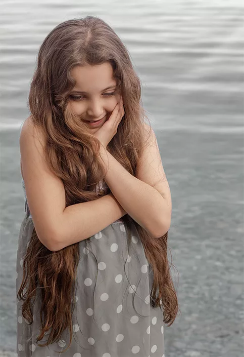 Young girl smiling softly outdoors during a natural lifestyle photography session
