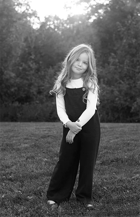 Black and white portrait of a young girl standing outdoors during a family photography session