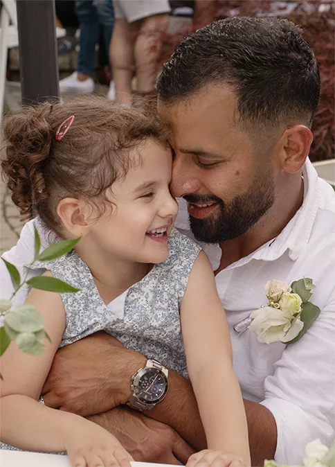 Father hugging and laughing with his young daughter during a family celebration