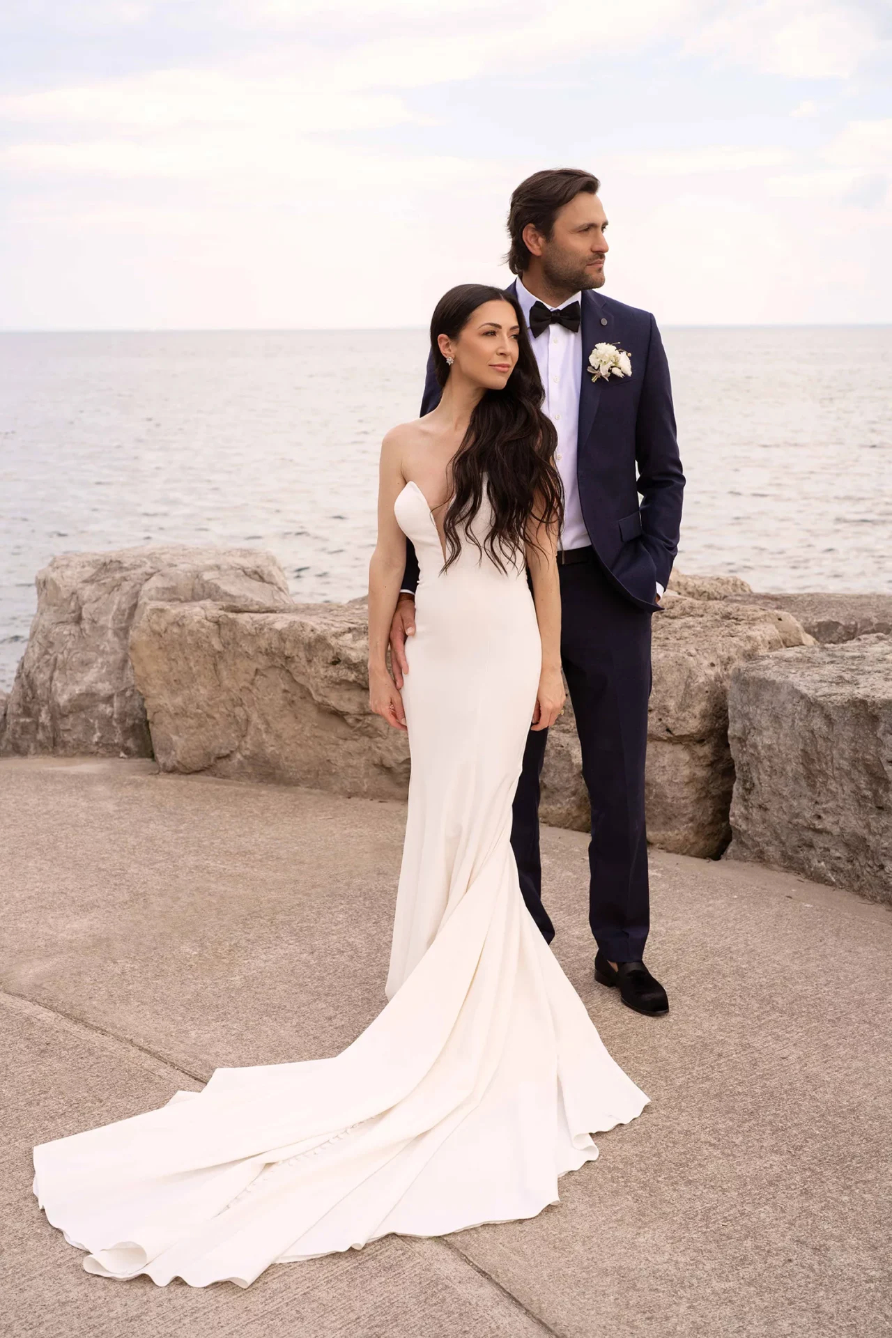 Bride and groom posing together by the water during a wedding photography session