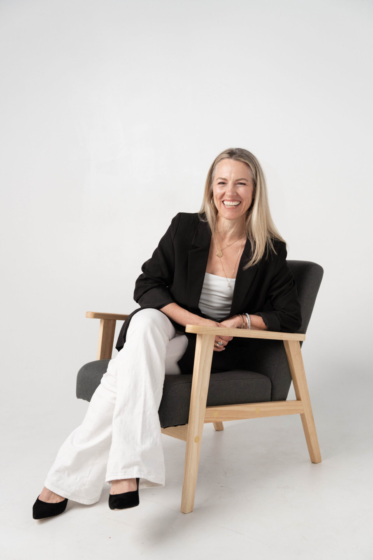 Smiling female business owner seated in a chair during a professional branding photography session