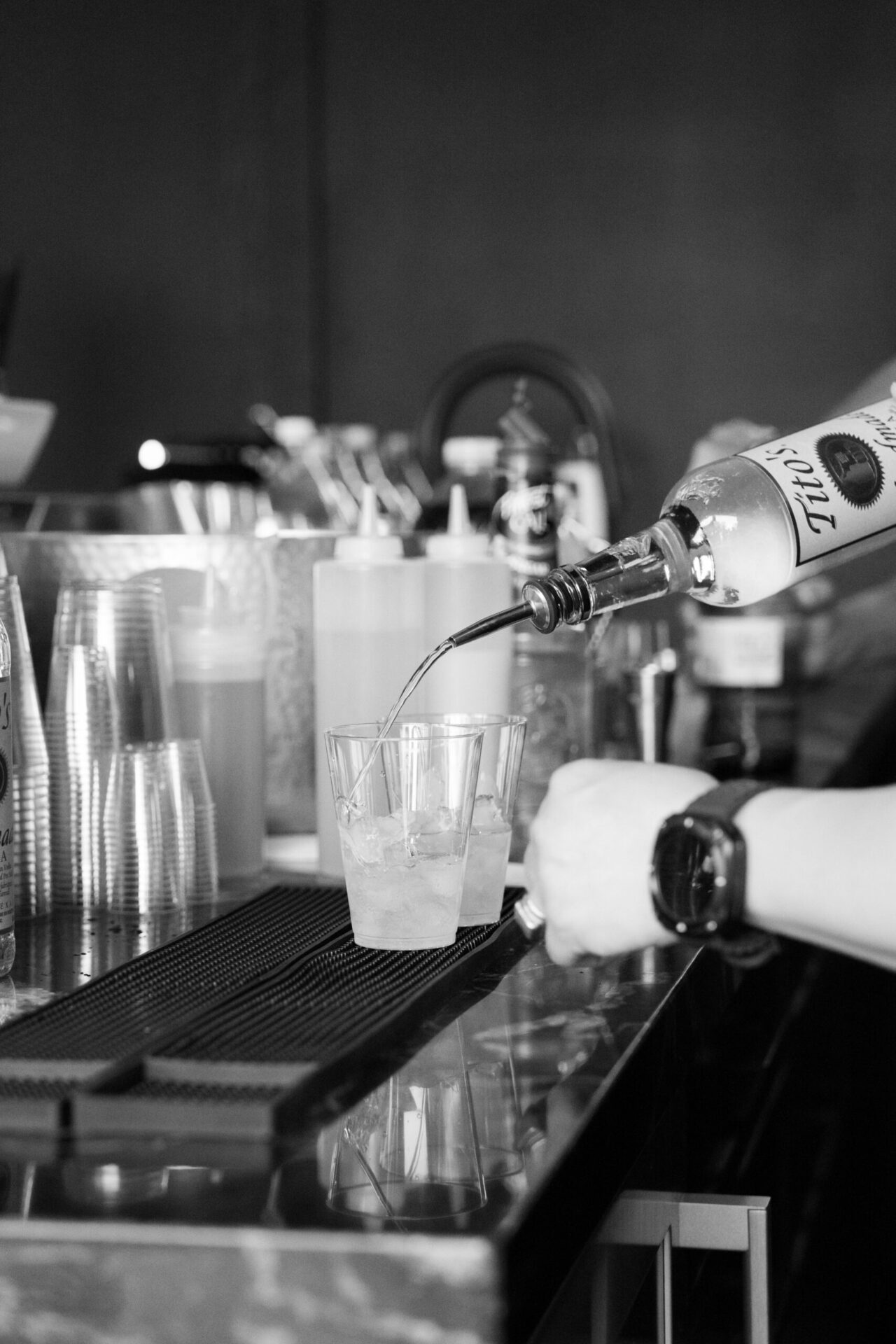 Black and white event photo of drinks being prepared behind a bar during a celebration