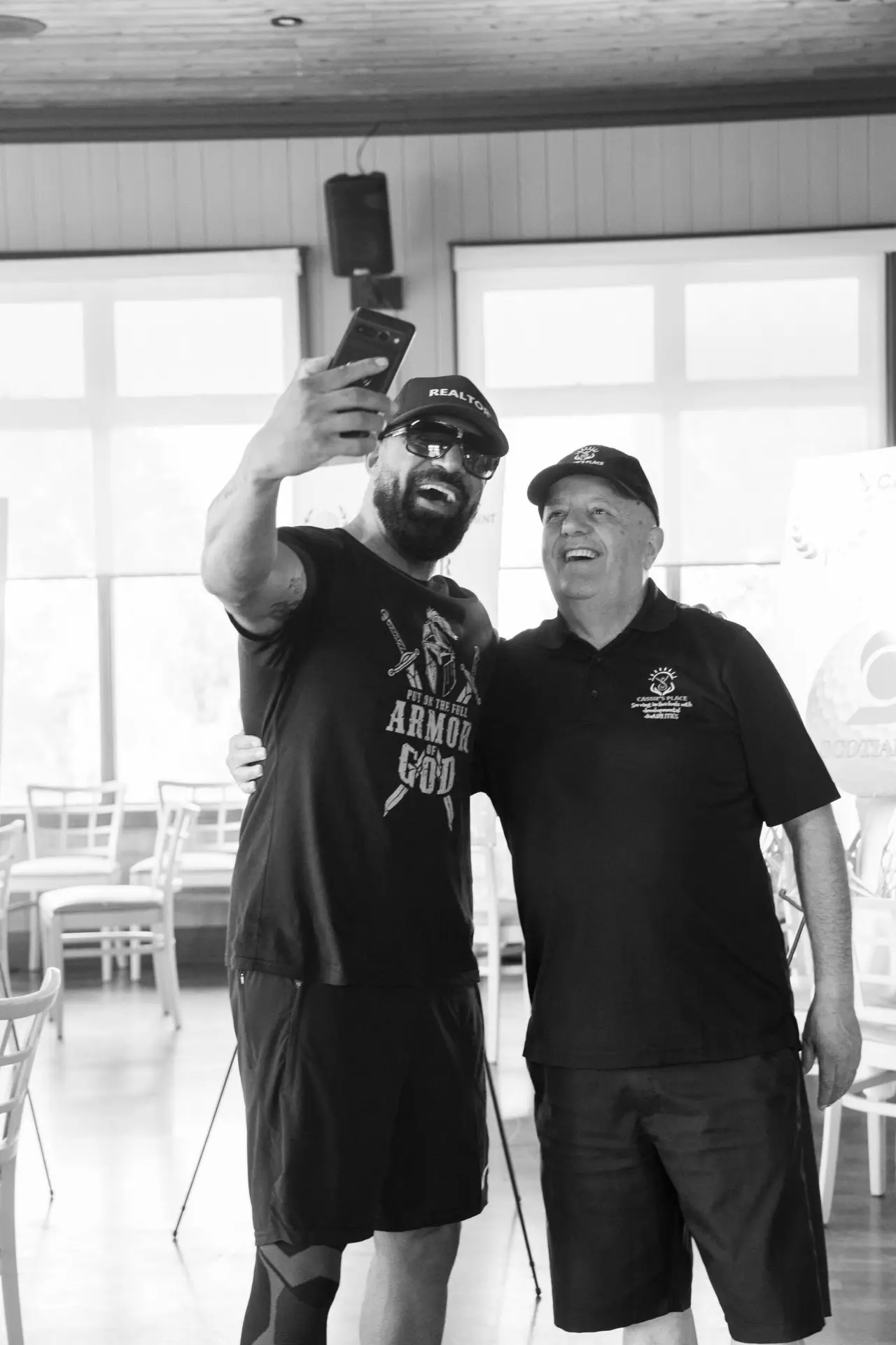 Black and white candid photograph of two men smiling together at an event