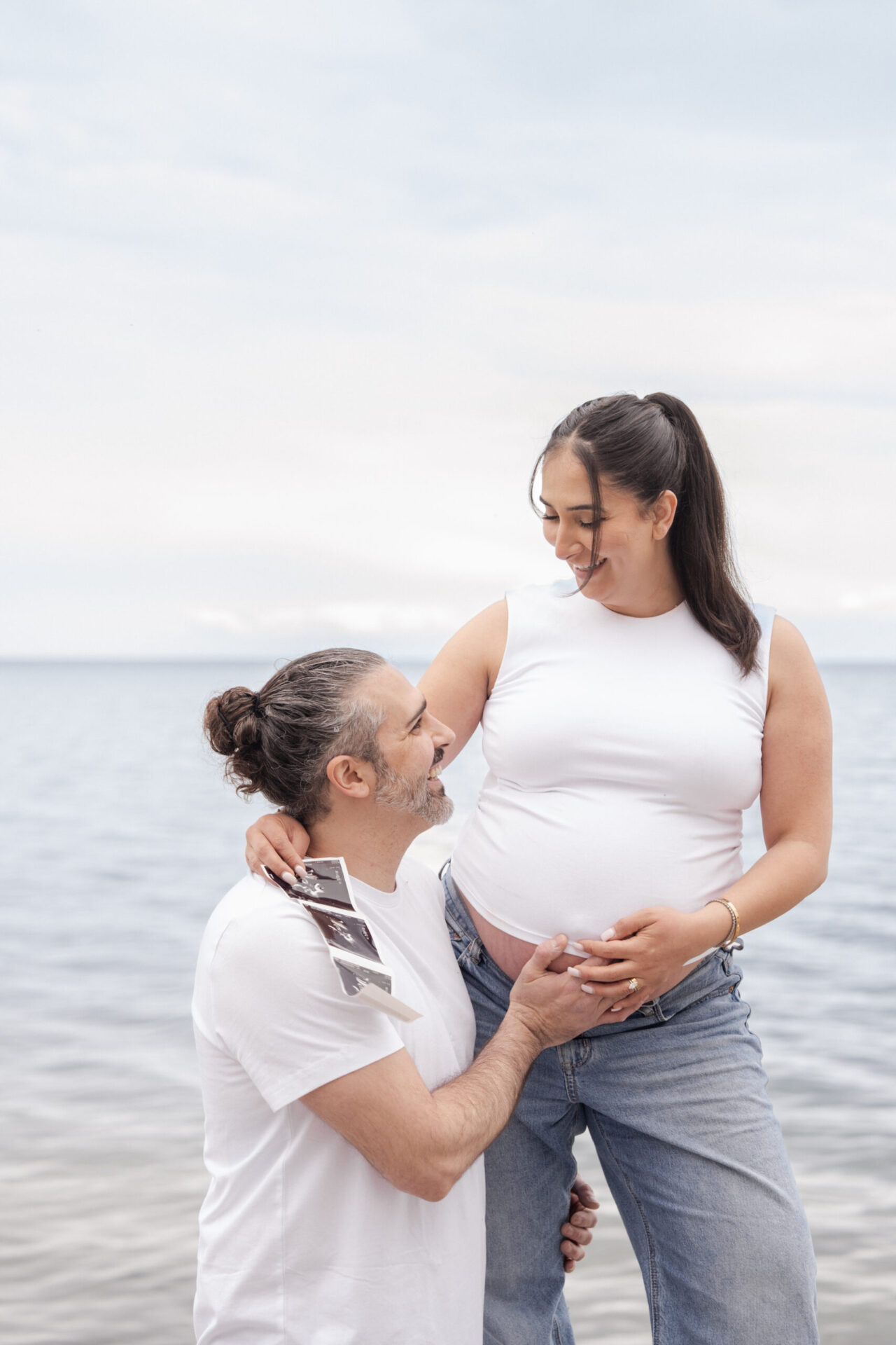 Expecting mother and partner sharing a quiet moment by the water during a maternity session