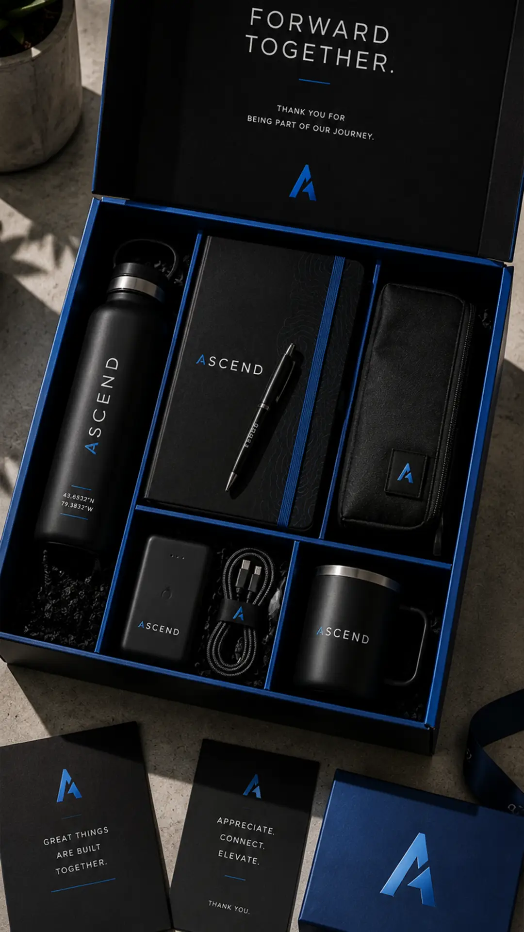 Premium black and blue corporate gift box with branded drinkware, notebook, pen and tech accessories