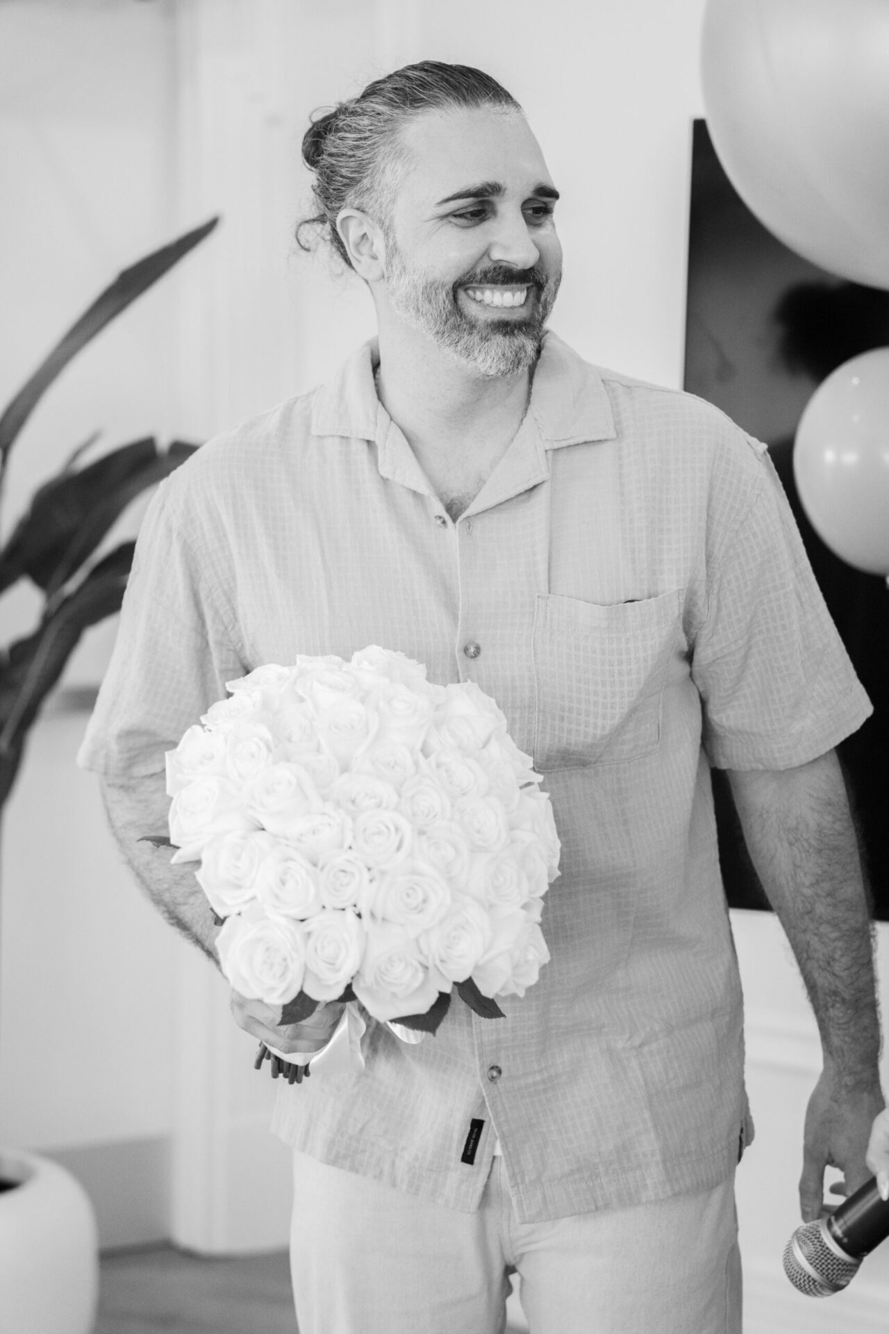 Black and white portrait of a man holding a bouquet of white flowers at a wedding or celebration