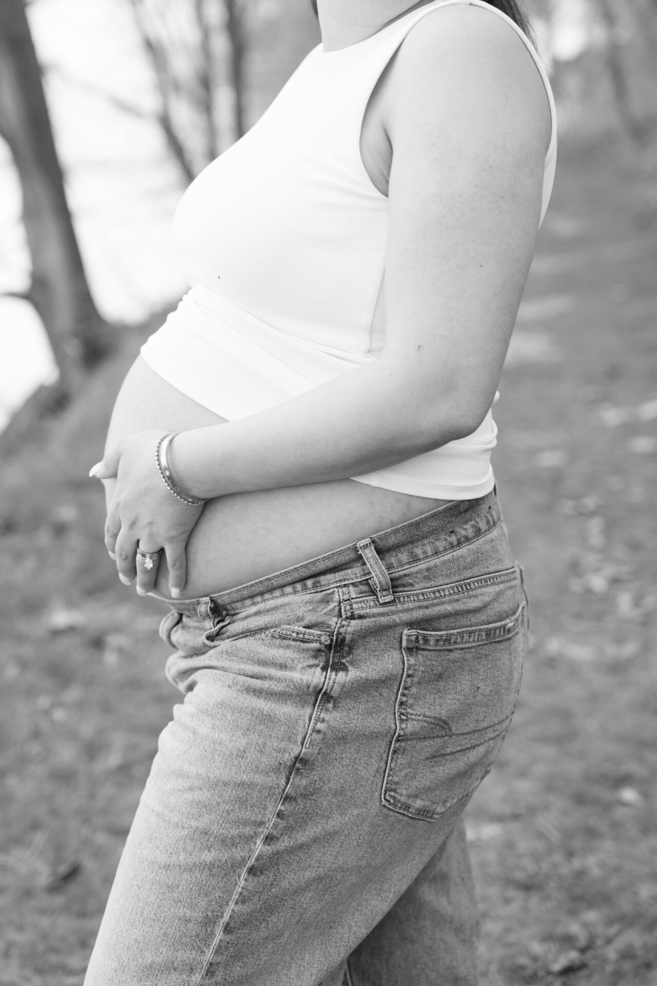 Black and white close-up of an expecting mother holding her baby bump during a maternity session
